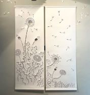 A papercut on white paper of dandelions with fluffy pappi pieces floating away